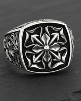 Top-down view of a sterling silver Maltese Cross ring, highlighting the polished cross against the dark oxidized background.