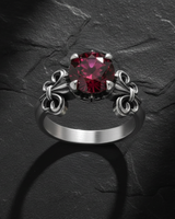 Gold-toned fleur-de-lis ring with deep red ruby displaying intricate crown setting and French heraldic design