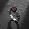 Sterling silver fleur-de-lis ring with red ruby in ornate crown setting on dark slate background