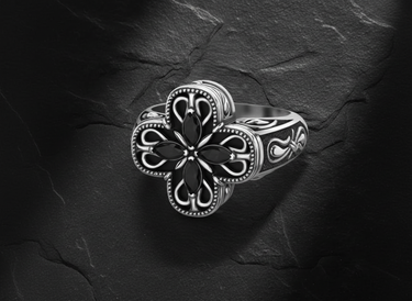 Side angle view of ornate cross ring showing detailed scrollwork band and beaded edges with gemstone setting