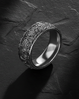 Angled view of handcrafted silver ring highlighting intricate floral scrollwork and oxidized finish details