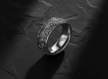 Angled view of handcrafted silver ring highlighting intricate floral scrollwork and oxidized finish details
