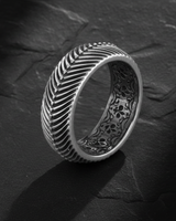 Side angle view of wide band herringbone ring showing geometric texture and filigree interior detail