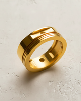 Gold vermeil piston ring featuring recessed grooves and circular cutouts displayed on a textured white background