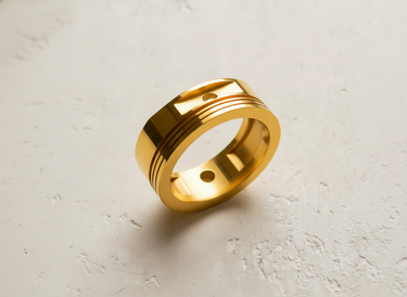 Gold vermeil piston ring featuring recessed grooves and circular cutouts displayed on a textured white background