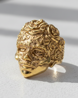 Gold vermeil sugar skull ring with a detailed rose headpiece and forehead cross, shown in bright sunlight on a white surface.