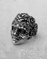 Oxidized silver sugar skull ring showcasing intricate scrollwork and floral details, angled on a textured gray background.