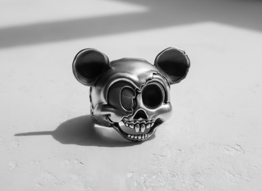 Oxidized sterling silver cartoon skull ring in black and white, highlighting the split-face detail and shadow.
