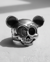 Silver Cartoon Skull Ring with an oxidized finish, showing the split-face design on a white textured surface.