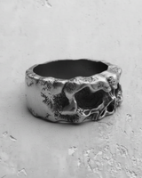 Side profile of the wide band silver skull ring, detailing the unique molten metal texture on the 925 silver surface.