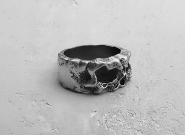 Side profile of the wide band silver skull ring, detailing the unique molten metal texture on the 925 silver surface.
