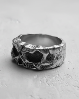 Angled view of the handcrafted silver skull ring, highlighting the weathered, oxidized finish and the skull's profile.