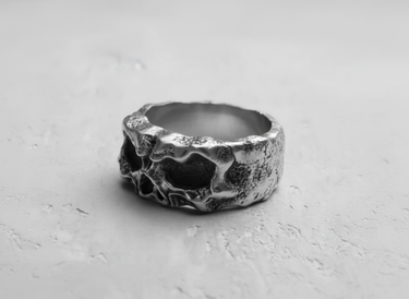 Angled view of the handcrafted silver skull ring, highlighting the weathered, oxidized finish and the skull's profile.