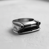 Silver classic car ring showing the detailed front grille, headlights, and band on a textured light grey surface.