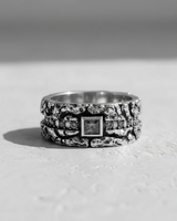 Front view of a rugged, textured gemstone ring for men, showing the square center stone and oxidized silver details in B&W.