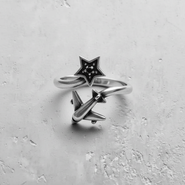 Overhead view of a sterling silver airplane star ring with an oxidized finish, highlighting the star's detailed gemstone settings.