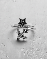 Silver airplane star ring with an oxidized finish showing the open band design on a textured white surface.