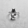 Silver airplane star ring with an oxidized finish showing the open band design on a textured white surface.