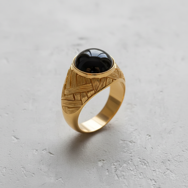 Silver basketweave cabochon ring with a polished black stone, showcasing the intricate, textured band design on a light surface.