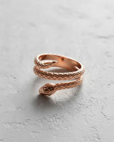 Rose gold vermeil silver snake ring with a close-up on the snake head and coiled body on a light grey background.