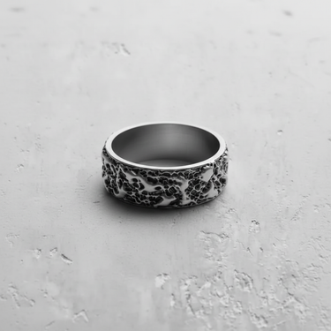A sterling silver molten texture ring with oxidized recesses, highlighting the deep, lava-like grooves on a light gray surface.