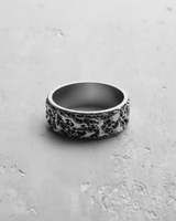 Side view of a wide band textured silver ring, showing its rugged, molten-lava-like surface and brushed interior.