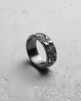Angled shot of a handcrafted textured silver ring, detailing the abstract raised forms and deep, porous metalwork.