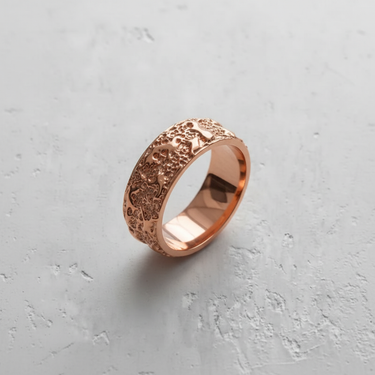 Rose gold plated textured silver ring with a wide band and intricate organic, coral-like pattern on a light background.