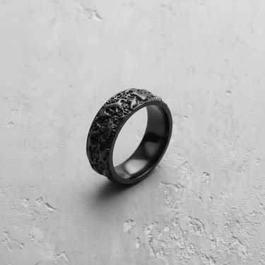 Silver molten texture ring with a matte black rhodium plating, showing its irregular organic surface on a concrete background.