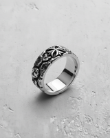 Angled view of the textured silver cross ring, highlighting the rough band, central emblem, and polished inner shank.