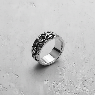Angled view of the textured silver cross ring, highlighting the rough band, central emblem, and polished inner shank.