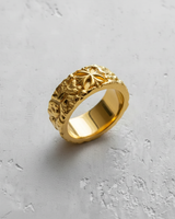 Men's 14K gold vermeil silver cross ring with a rough, organic texture, shown from an angle on a light grey concrete surface.