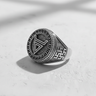 Top-down view of the silver geometric signet ring, featuring its central triangle symbol and sunburst border on a white surface.