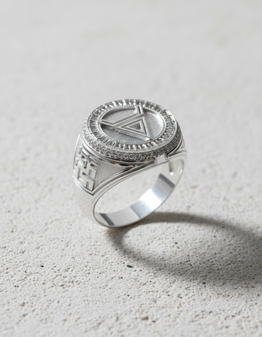Polished sterling silver geometric symbol ring with an inverted triangle and pave stone halo, shown on a light concrete surface.
