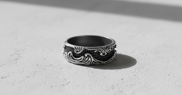 Oxidized Silver Wave Grid Ring with high-contrast baroque wave details, displayed in direct sunlight on a textured background.