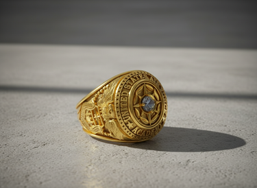 Silver Air Force Academy ring with a blue gemstone, showing the detailed eagle emblem on the side, on a concrete surface.