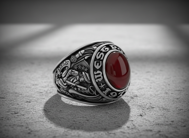 Silver West Point ring with oxidized details, showcasing the US Military Academy crest and red stone on a textured surface.