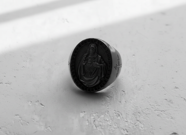 Dramatic studio shot of the Sacred Heart Jesus ring, with shadows emphasizing its bold signet shape and oxidized finish.