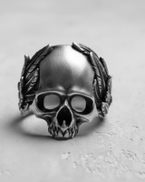 Front view of the Silver Laurel Skull Ring in oxidized 925 sterling silver, showcasing detailed carving on a light textured surface.