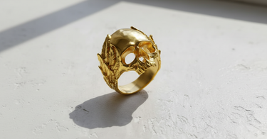 Gold plated Silver Skull Wreath Ring shown at an angle in natural sunlight, highlighting the polished skull and laurel details.