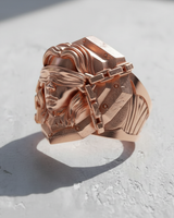 Rose gold plated Blind Justice Ring shown at an angle on a white textured surface, highlighting the detailed chains.