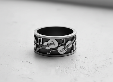 Oxidized sterling silver music ring with detailed guitar and violin design, showcasing the contrast and fine craftsmanship.