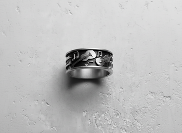 Top-down view of the handcrafted music themed band ring, displaying the continuous pattern of instruments and notes.