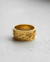 14K gold vermeil music ring with embossed guitar and violin designs shown on a light gray textured surface.
