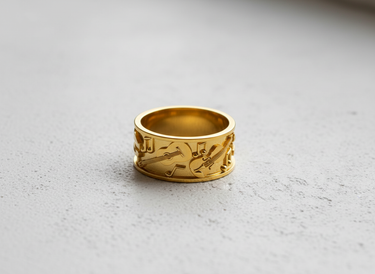 14K gold vermeil music ring with embossed guitar and violin designs shown on a light gray textured surface.