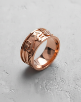 Rose gold plated silver music ring showcasing embossed piano keys and musical notes on a textured white surface.