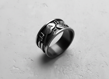 Angled shot of the handcrafted silver music ring, highlighting the 3D relief of the guitar and violin design.