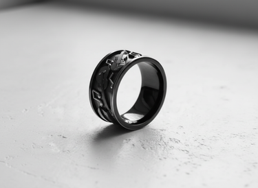 Silver music ring with black rhodium plating, showing embossed musical notes and instruments from an angled side view.