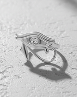 Polished 925 sterling silver Eye of Horus ring with a central bezel-set gemstone, shown on a textured white surface.