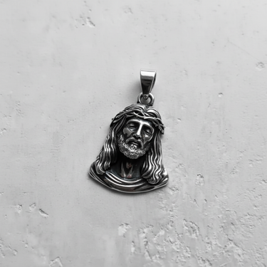 Angled side view of religious sterling silver pendant displaying the bail and three-dimensional relief of the Jesus bust